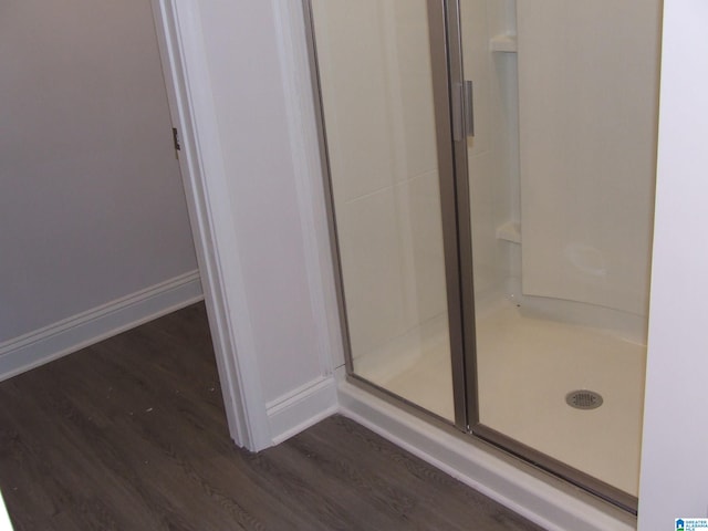 bathroom with wood-type flooring and a shower with door