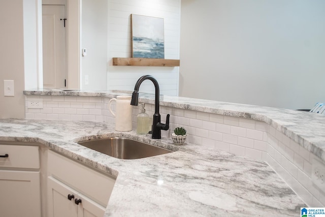 kitchen with white cabinetry, backsplash, and sink