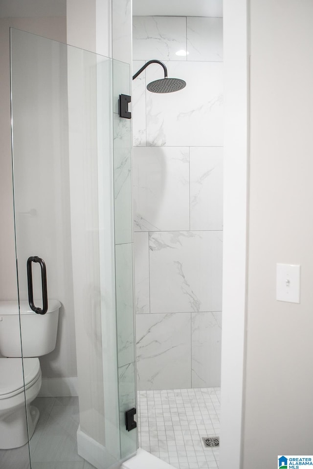 bathroom featuring tile floors, a shower with shower door, and toilet