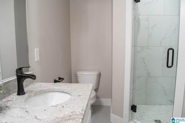 bathroom with an enclosed shower, vanity, and toilet