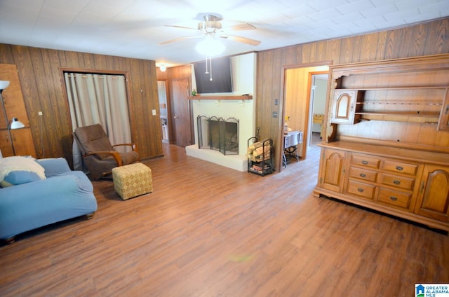 living room featuring light hardwood / wood-style floors, ceiling fan, and wooden walls