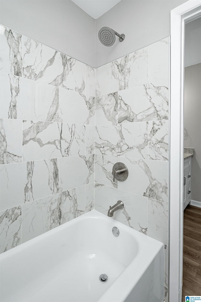 bathroom featuring tiled shower / bath, hardwood / wood-style flooring, and vanity