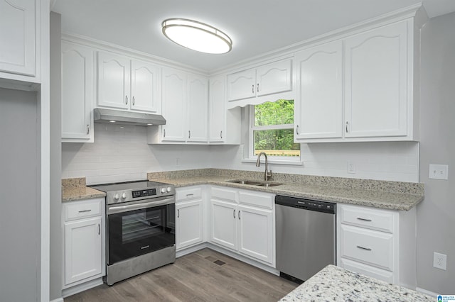 kitchen with appliances with stainless steel finishes, hardwood / wood-style flooring, white cabinets, light stone countertops, and sink