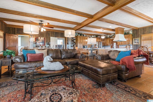 living room featuring light tile floors, wooden walls, ceiling fan, and beamed ceiling
