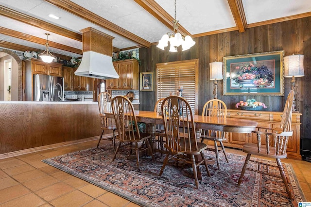 dining space featuring a chandelier, beamed ceiling, wood walls, and light tile floors