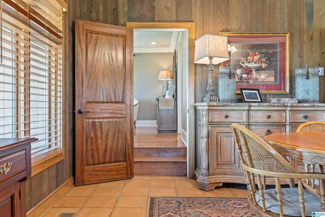 kitchen featuring light tile floors, crown molding, wooden walls, and light stone counters