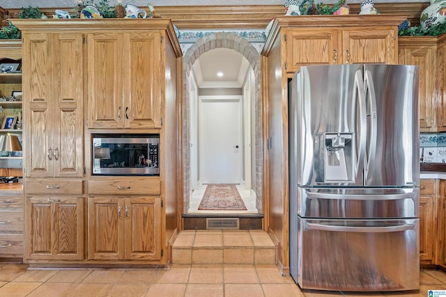 kitchen featuring crown molding, appliances with stainless steel finishes, and light tile floors