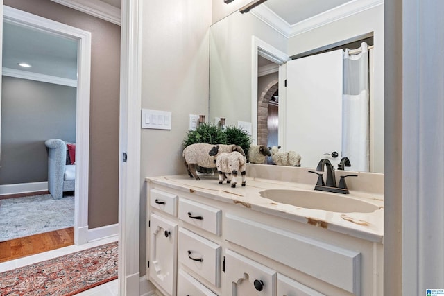 bathroom featuring hardwood / wood-style floors, ornamental molding, and vanity