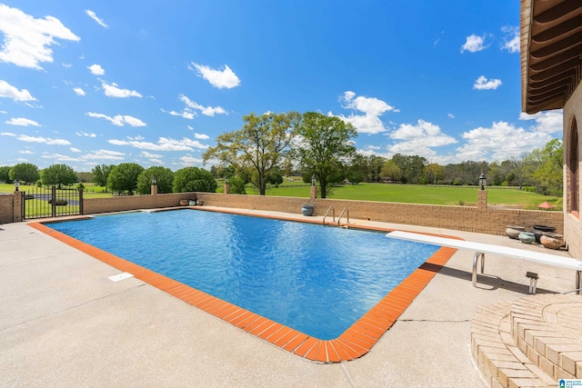 view of swimming pool featuring a diving board, a yard, and a patio area
