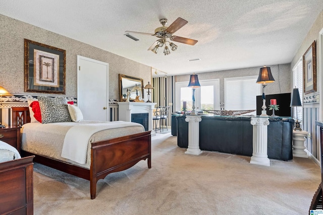 carpeted bedroom with a textured ceiling, ceiling fan, and decorative columns