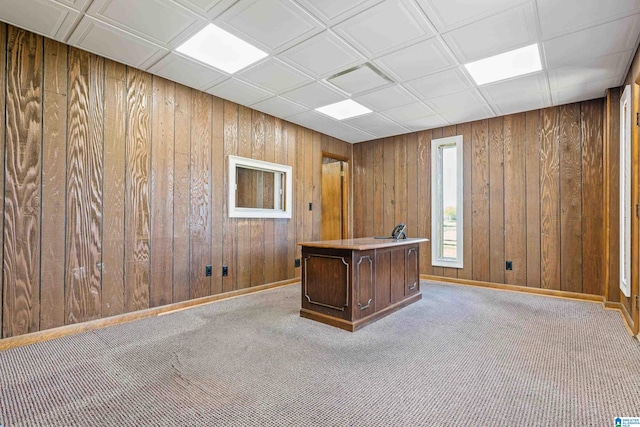 unfurnished office with wood walls, a drop ceiling, and carpet