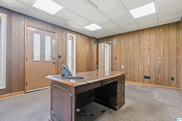 unfurnished office with a paneled ceiling, dark colored carpet, and wood walls