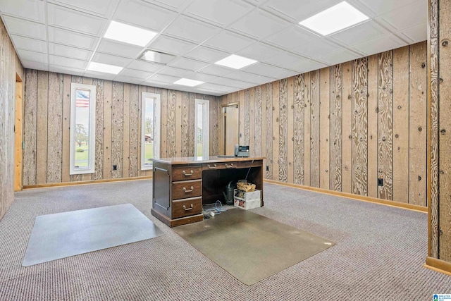 carpeted office with wood walls and a drop ceiling