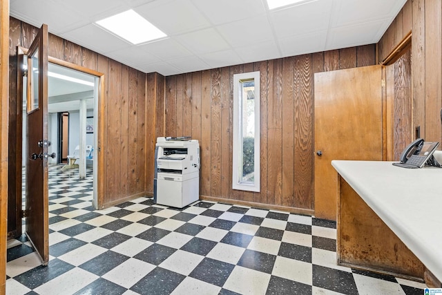 interior space with wooden walls, a paneled ceiling, and light tile floors
