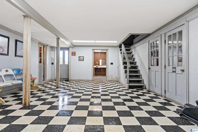 basement with light tile floors and ornamental molding
