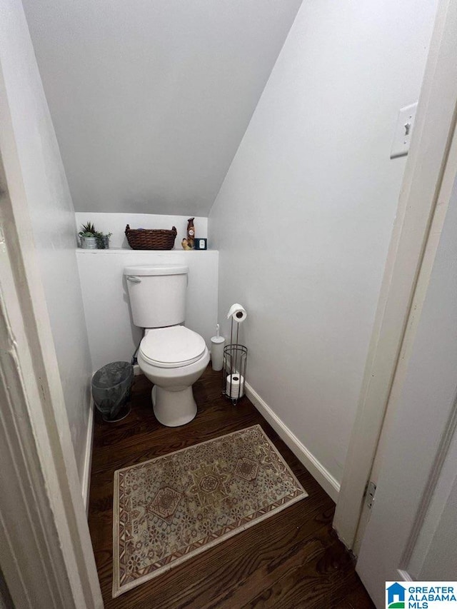 bathroom featuring toilet, hardwood / wood-style floors, and vaulted ceiling