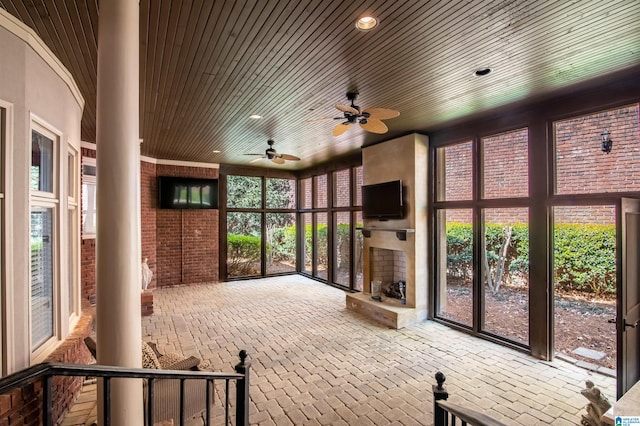 unfurnished sunroom featuring decorative columns, wood ceiling, and ceiling fan