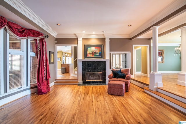 sitting room featuring ornate columns, crown molding, a tile fireplace, and hardwood / wood-style floors