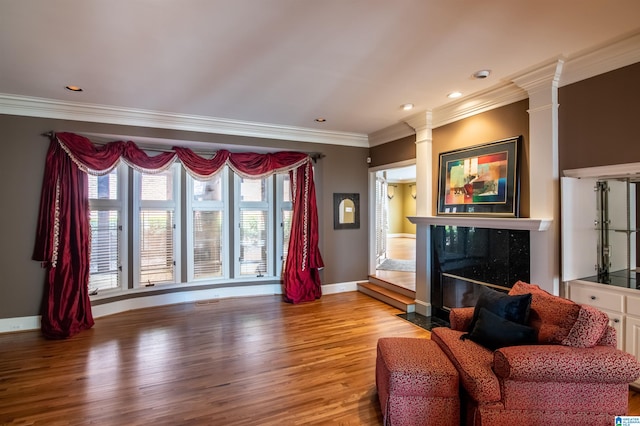 living room with decorative columns, light hardwood / wood-style floors, and ornamental molding