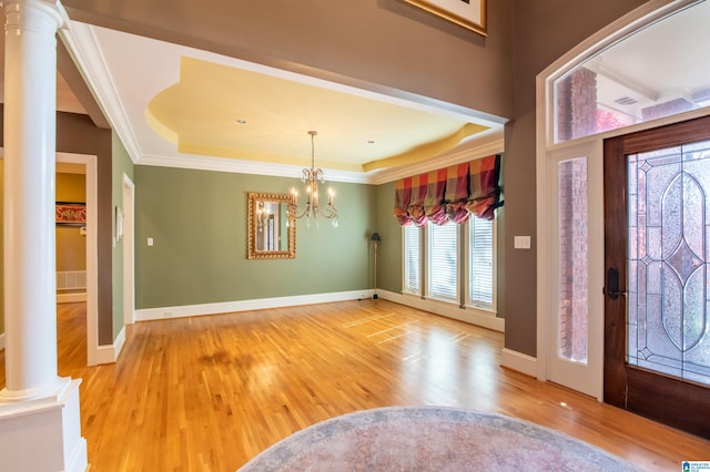 foyer entrance featuring a raised ceiling, decorative columns, and hardwood / wood-style floors