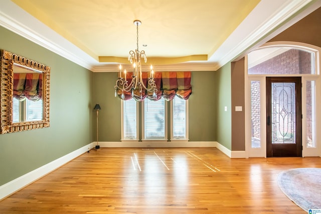 interior space with crown molding, a notable chandelier, wood-type flooring, and plenty of natural light