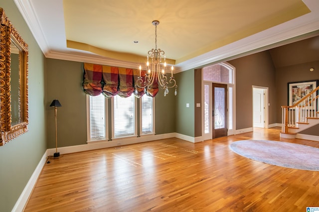 interior space featuring a tray ceiling, a chandelier, and light wood-type flooring