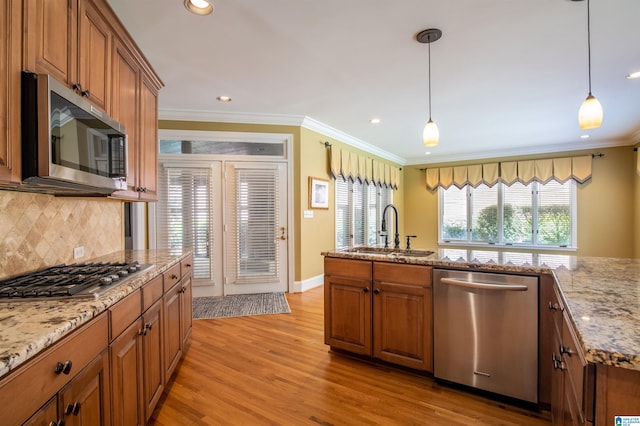 kitchen with sink, stainless steel appliances, decorative light fixtures, ornamental molding, and light hardwood / wood-style flooring