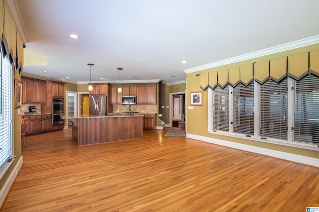 kitchen with appliances with stainless steel finishes, light hardwood / wood-style flooring, decorative light fixtures, and a kitchen island