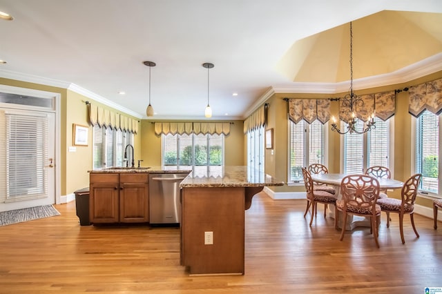 kitchen featuring hanging light fixtures, a kitchen island with sink, light wood-type flooring, dishwasher, and sink