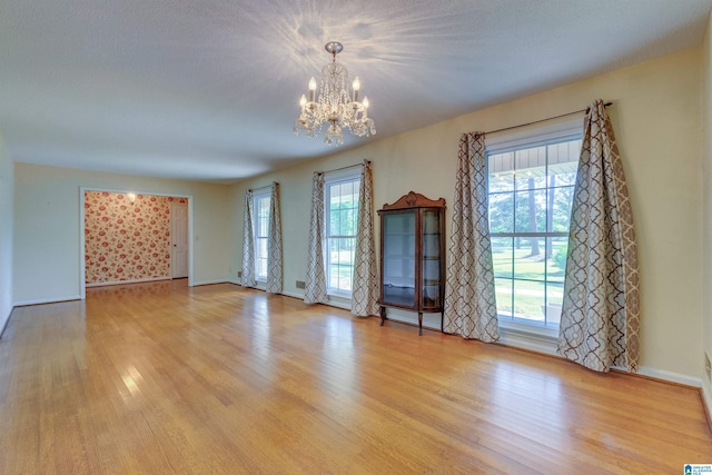 empty room featuring an inviting chandelier and light wood-type flooring