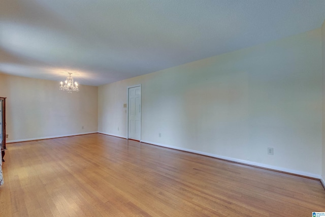 empty room featuring light hardwood / wood-style floors and an inviting chandelier