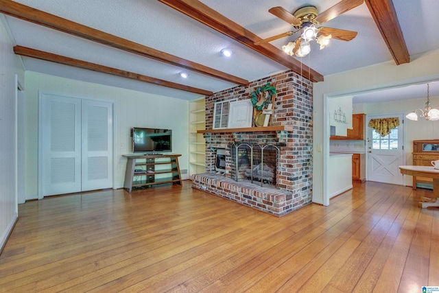 living room featuring a fireplace, ceiling fan with notable chandelier, brick wall, beam ceiling, and light hardwood / wood-style floors