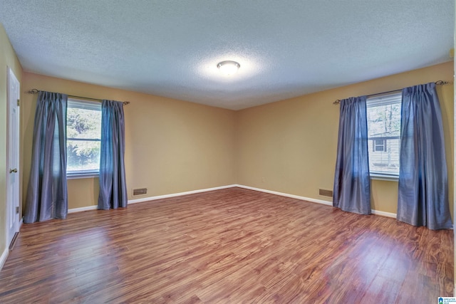 empty room featuring dark hardwood / wood-style flooring, plenty of natural light, and a textured ceiling