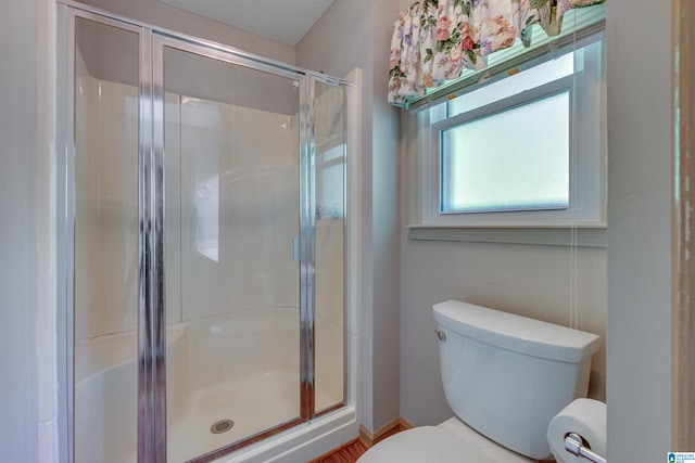 bathroom featuring a shower with shower door, toilet, and a textured ceiling