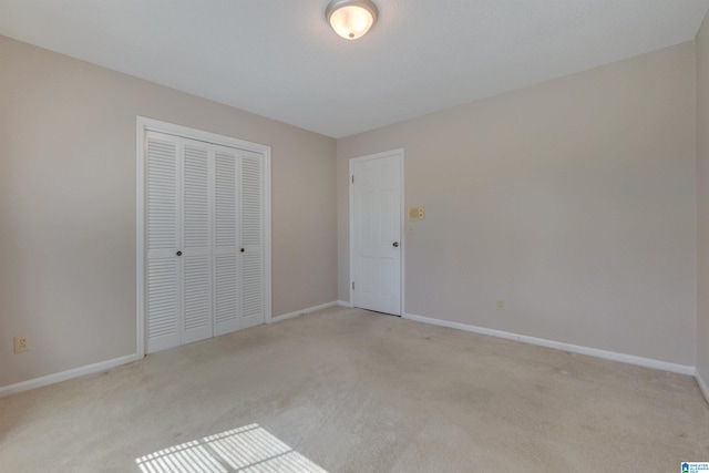 unfurnished bedroom with light colored carpet and a closet