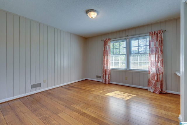 spare room with a textured ceiling and light wood-type flooring