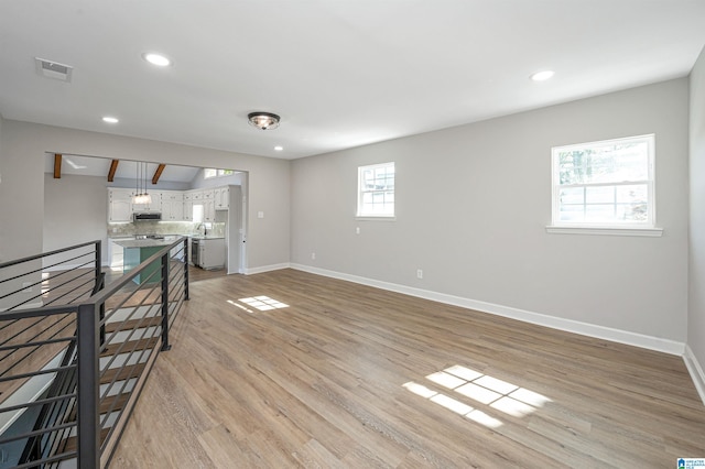 unfurnished living room featuring plenty of natural light, sink, and light wood-type flooring