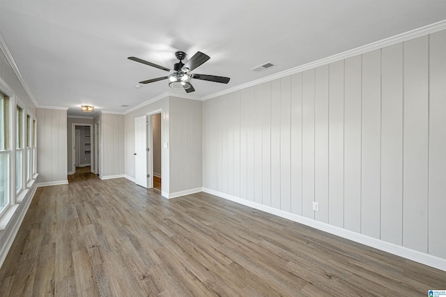 unfurnished room with light hardwood / wood-style floors, ceiling fan, wooden walls, and crown molding