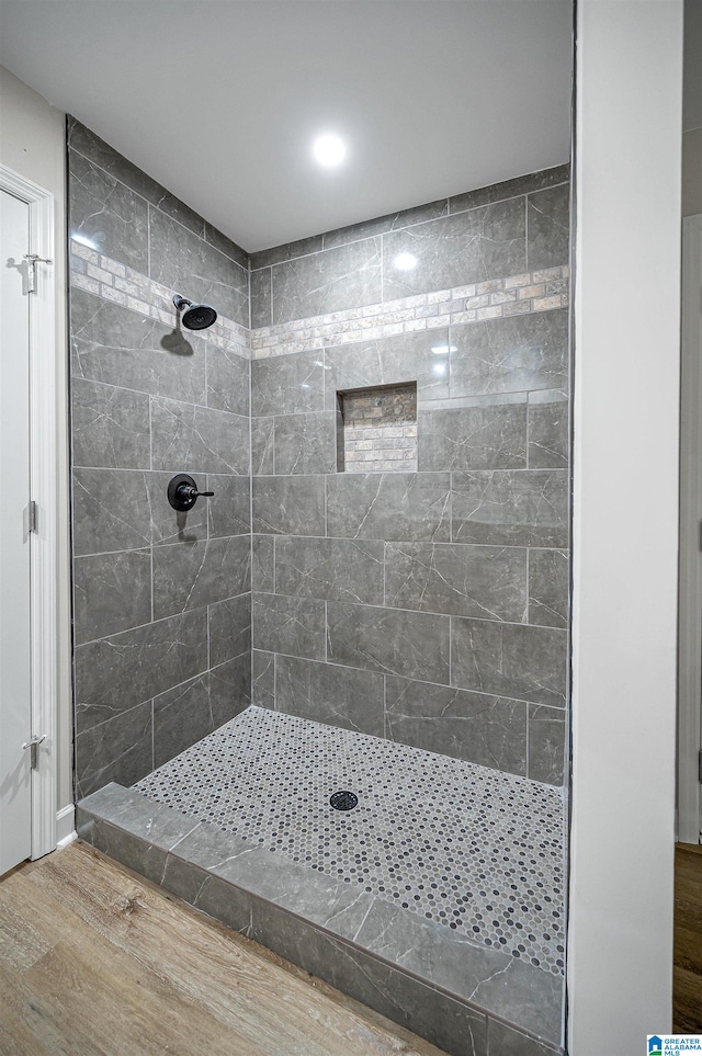 bathroom featuring hardwood / wood-style floors and a tile shower