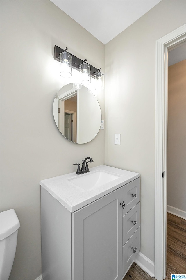 bathroom featuring wood-type flooring, toilet, and vanity