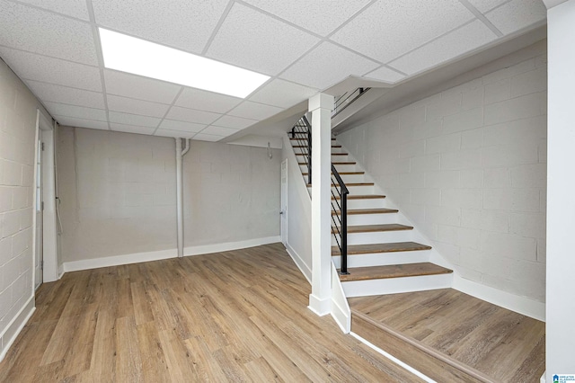 basement featuring light wood-type flooring and a drop ceiling