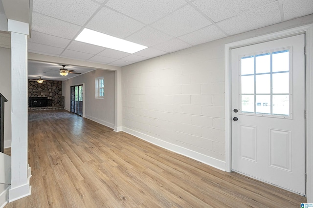 interior space featuring a stone fireplace, light hardwood / wood-style floors, a paneled ceiling, and ceiling fan