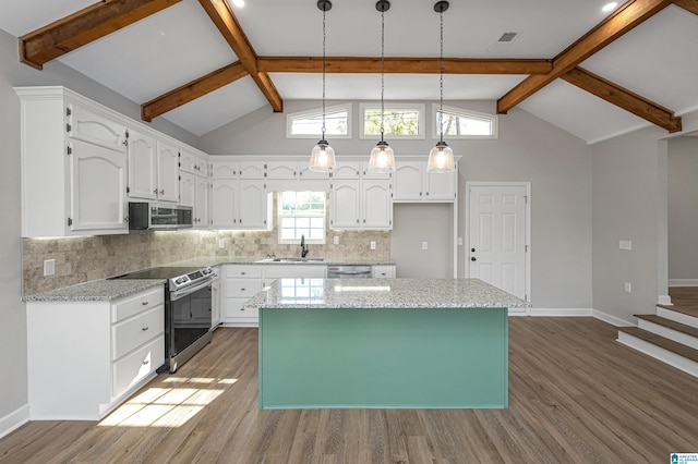 kitchen with stainless steel appliances, white cabinetry, tasteful backsplash, wood-type flooring, and a kitchen island