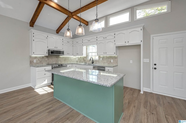 kitchen with stainless steel appliances, a center island, white cabinets, beam ceiling, and pendant lighting