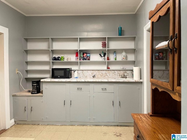 kitchen with ornamental molding, gray cabinetry, sink, and light tile floors