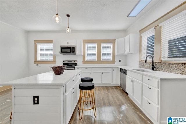 kitchen with pendant lighting, appliances with stainless steel finishes, plenty of natural light, and sink