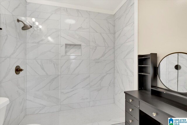 bathroom with a tile shower, toilet, and vanity