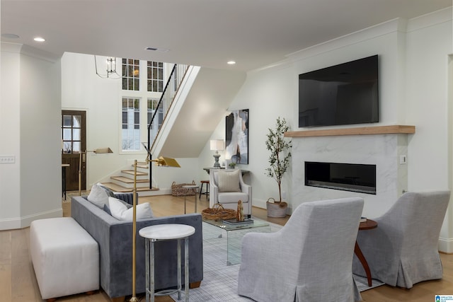 living room with hardwood / wood-style floors, crown molding, a fireplace, and a chandelier