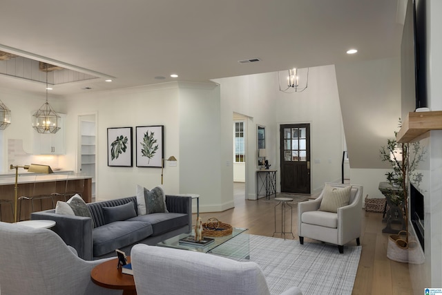 living room with a chandelier, ornamental molding, light hardwood / wood-style flooring, and built in features