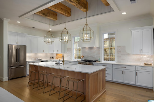 kitchen featuring white cabinets, stainless steel appliances, and a center island with sink